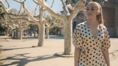 Puantiyeli genç ve çekici bir kadın. Şehir parkında güvenli bir şekilde yürüyor.