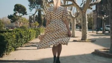 Arka planda, puantiyeli elbiseli güzel bir kadının eski güzel parkta koşarkenki görüntüleri var. 