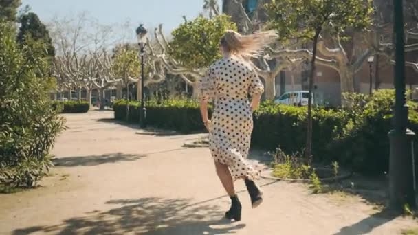 Puantiyeli Elbiseli Güzel Bir Kadının Eski Şehir Parkında Koşarkenki Görüntüsünü — Stok video