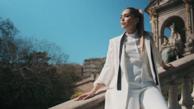 Beyaz takım elbiseli sosyetik bir kadının eski güzel mimarisi ile parktaki merdivenlerde poz verirken çekilmiş bir fotoğrafı. Geçiş aşısı