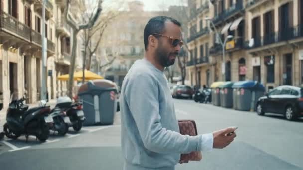 미디엄은 도로를 가로질러 스마트폰을 사업가가 선글라스를 장면을 촬영했다 일하러 — 비디오