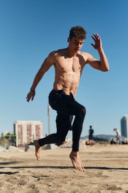 Şehir plajındaki işlevsel eğitim sırasında atlayan yakışıklı sporcu. Genç adam dışarıda çalışıyor.