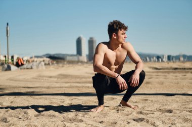 Şehir plajında spor yaparken dinlenen çekici genç bir adam.