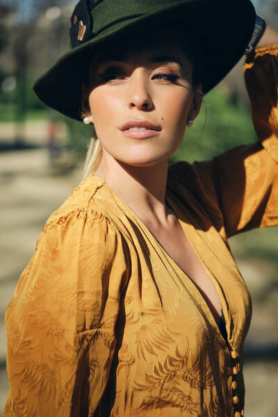 Portrait of young gorgeous woman wearing hat and confidently looking away outdoor
