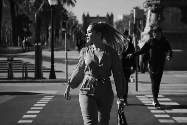 Portrait of young posh elegant woman crossing the road along city street. Black and white photo