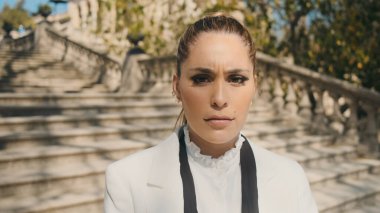 Kızgınlıkla eski şehir parkındaki merdivenlerde kameraya bakan güzel, üzgün bir kadın. Üzgün yüz ifadesi