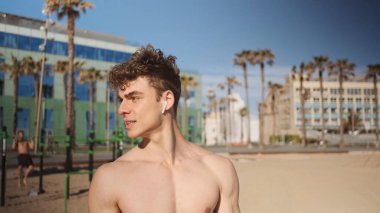 Açık havada çalışan, kablosuz kulaklıklı yakışıklı bir adamın portresi.