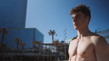 Kablosuz kulaklıklı çekici genç bir adamın portresi. Dikkatlice dışarıya bakıyor.