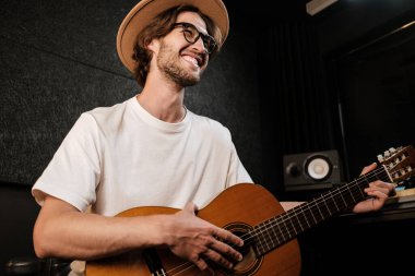 Çekici stil sahibi bir adam stüdyoda gitar çalıp şarkı söylüyor. Genç müzisyen modern ses stüdyosunda yeni şarkı kaydediyor.