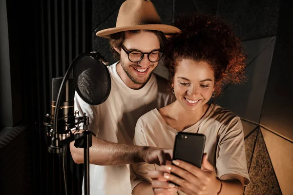 Vackra Par Stilfulla Sångare Använder Gärna Telefonen Tillsammans Modern Ljudinspelningsstudio — Stockfoto