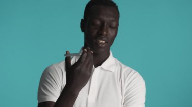 Çekici stil Afrikalı Amerikalı adam renkli arka planda akıllı telefondan sesli mesaj kaydediyor.
