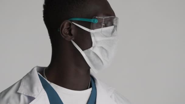 用防护眼镜和医疗面罩把年轻的非洲裔美国男医生关起来 自信地看着被隔离的摄像机 — 图库视频影像