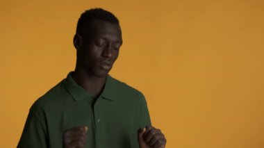 Çekici stil Afrikalı Amerikalı adam gözlerini kapatıp renkli arka planda dans ediyor.