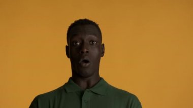 Genç afro-amerikan bir adam korkuyla renkli arka planda kameraya bakıyor. Bu benim ifadem değil.