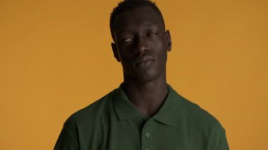 Genç rahatsız olmuş Afro-Amerikan bir adam gözlerini renkli arka planda gezdiriyor. Yorgun ifade