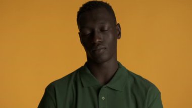 Genç, ciddi, Afro-Amerikan bir adam renkli arka planda kameraya hiç el sallamıyor. Anlaşmazlık ifadesi