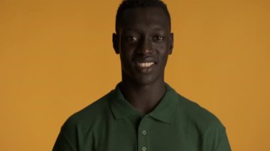 Yakışıklı, gülümseyen Afrikalı Amerikalı bir adamın renkli arka planda kameraya bakarken mutlu bir portresi.