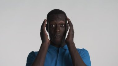 Yakışıklı, Afro-Amerikalı adam, şaşırtıcı bir şekilde gri arka plandan kameraya bakıyor. Vay canına.