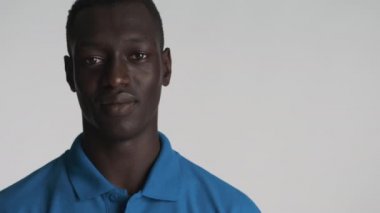Yakışıklı, gülümseyen Afrikalı Amerikalı bir adamın portresi. Gri arka plandan kameraya bakıyor.