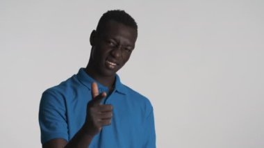 Yakışıklı, havalı, Afro-Amerikan bir adam gri arka planda başparmak hareketi yapıyor. Sen ve ben.