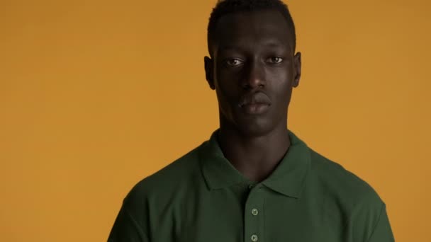 若い深刻なアフリカ系アメリカ人男性積極的にカラフルな背景にカメラを見て 顔の表情 — ストック動画