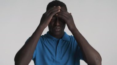 Genç üzgün Afrikalı Amerikalı adam duygusal olarak başını gri arka planda tutuyor. Yorgun ifade