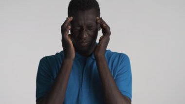 Genç yorgun Afrikalı Amerikalı adam baş ağrısından parmaklarıyla tapınaklara masaj yapıyor.