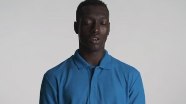 Kafası karışmış genç Afrikalı Amerikalı adam gri arka planda silah işareti gösteriyor. Silah atışı hareketi.