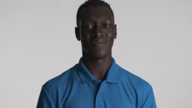 Yakışıklı, gülümseyen, Afro-Amerikan adam mutlu bir şekilde parmağını kaldırıyor ve gri arka planda bir jest yapıyor. İfade gibi