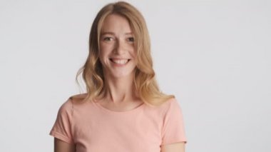 Neşeli sarışın kız gri arka planda kameraya neşeyle evet diyor. İfadeyi kabul et