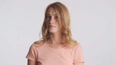 Çekici sarışın kız kameraya dikkatlice bakıyor gri arka planda el sallamıyor. Anlaşmazlık ifadesi