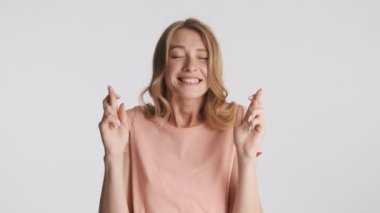 Gri arka plan için kameraya dua eden parmaklarını çapraz yapmış oldukça heyecanlı bir kız. Lütfen ifade et