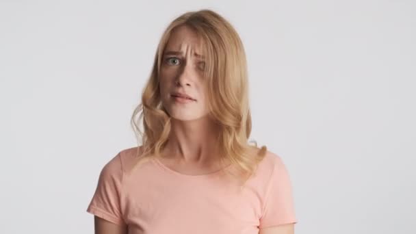 若い怖がって金髪の女性は灰色の背景にジェスチャーを振っていません 意見の相違 — ストック動画
