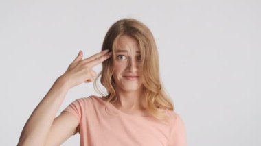 Güzel, komik, sarışın kız gri arka planda silah işareti göstermekten mutlu. Silah atışı hareketi.