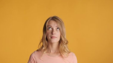 Oldukça neşeli sarışın bir kız, şaşırtıcı bir şekilde renkli arka planda kameraya bakıyor. Yeni fikir ifadesi