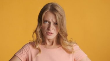 Genç kızgın sarışın kadın saldırganca renkli arka planda kameraya bakıyor. Tehlikeli bir ifade.