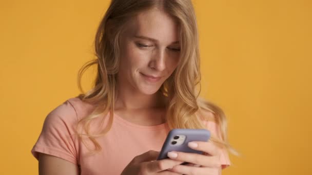 カラフルな背景の上にスマートフォンを使用して熱心に美しい金髪の女の子を閉じます 式の入力 — ストック動画