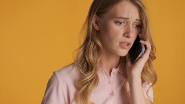 迷人的 令人失望的金发女孩在智能手机上用五颜六色的背景说话 严肃的言论 — 图库视频影像