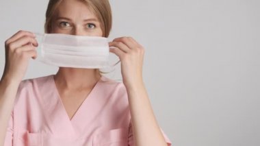 Gri arka planda tıbbi maske takan güzel bir bayan doktor. Güvenlik kavramı