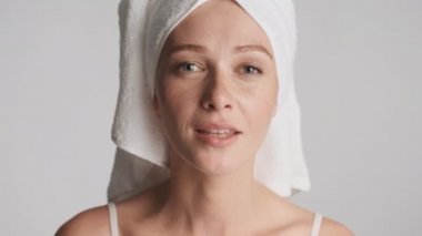 Kafasında havluyla güzel bir kadını kapat. Gri arka planda temiz yüzüne dokun.