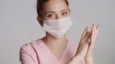 Tıbbi maskeli genç bayan doktoru kapatın. Beyaz arka planda ellerini güvenli bir şekilde yıkıyor.