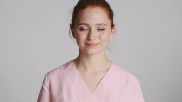 若い美しい自信のある医師が喜んでカメラにOkジェスチャーを示し 灰色の背景に笑みを浮かべて いいですか — ストック動画