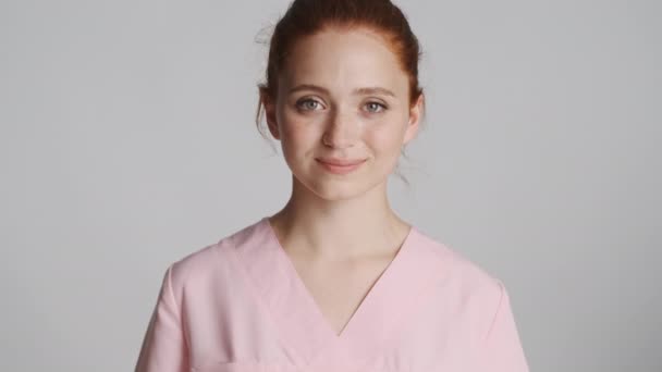 Joven Hermosa Enfermera Sonriente Felizmente Mirando Cámara Sobre Fondo Gris — Vídeos de Stock