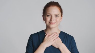 Genç, güzel, gülümseyen hemşire, mutlu bir şekilde elini beyaz arka planda tutuyor. Yumuşak ve dokunaklı ifade