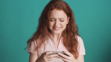 Akıllı telefondan oynayan ve renkli arka planda kaybeden çekici kızıl saçlı kız. Oyun bitti.