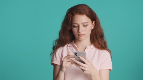 吸引人的无聊红头发女孩使用智能手机没有兴趣的彩色背景 无聊的表达方式 — 图库视频影像