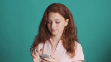 Güzel, kızıl saçlı bir kız. Akıllı telefondan arkadaşlarıyla sohbet ediyor ve renkli bir geçmişle gülümsüyor.