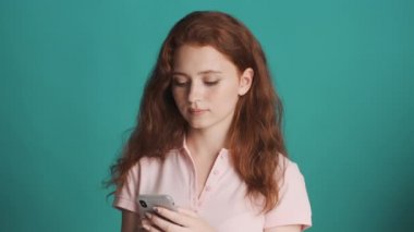 Çekici, konsantre, kızıl saçlı bir kız. Renkli bir geçmişle akıllı telefondan arkadaşlarıyla sohbet ediyor.