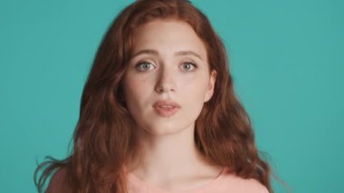 Heyecanlı kızıl saçlı güzel bir kızın portresi. Parmağını kaldırıyor. Renkli arka plan üzerinde yeni bir fikri var.