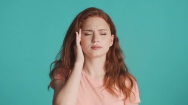 Renkli arkaplanda baş ağrısı gösteren yorgun kızıl saçlı kızın portresi